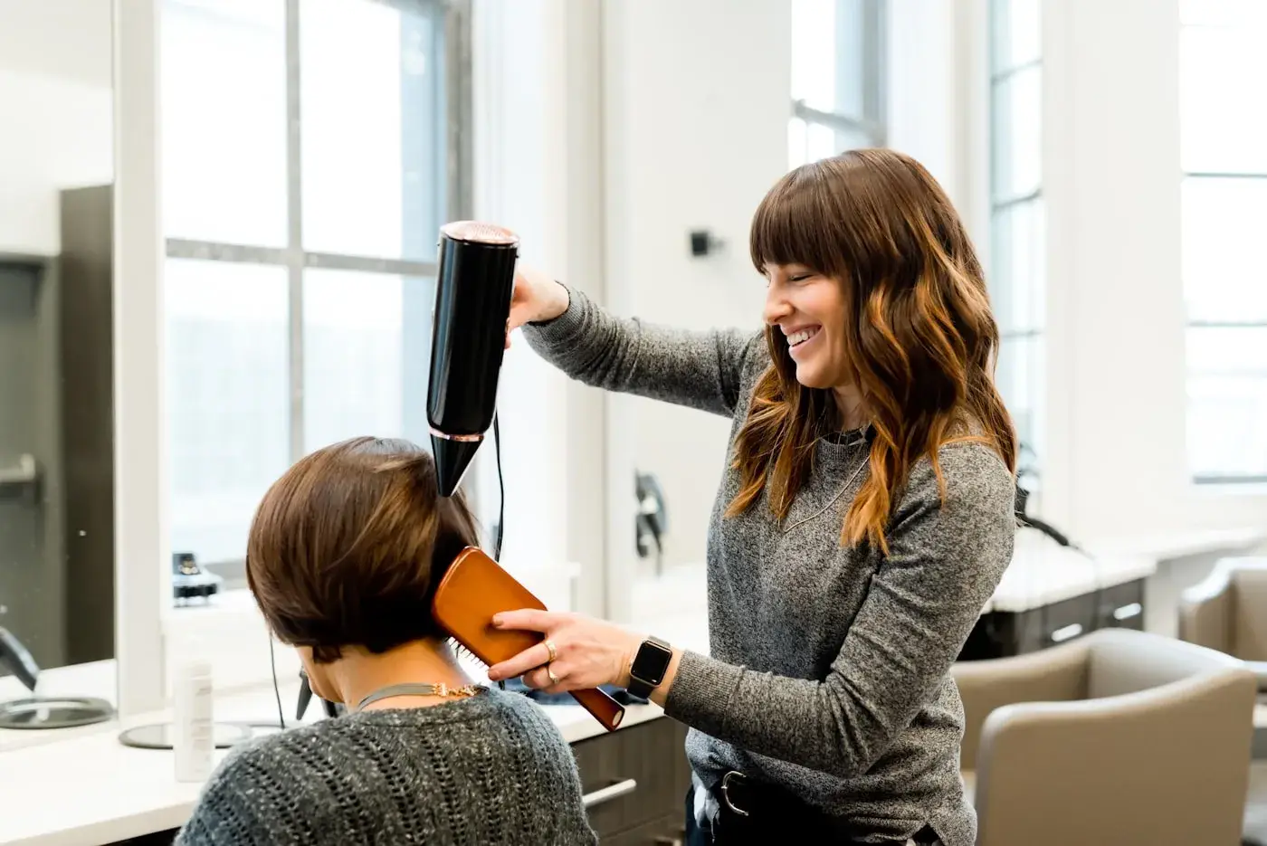 Coiffeuse réalisant un brushing en salon lumineux