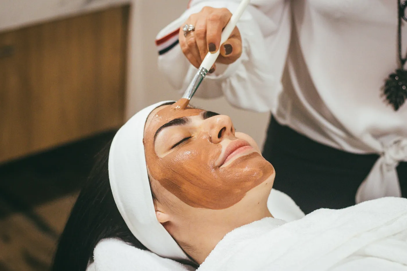 Application d'un masque de soin sur le visage d'une cliente